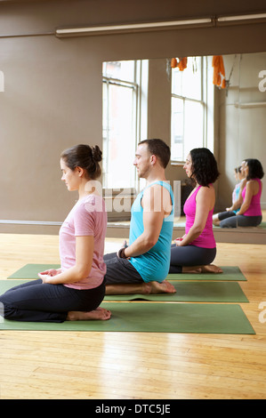 Menschen, die kniend im Yoga-Kurs Stockfoto