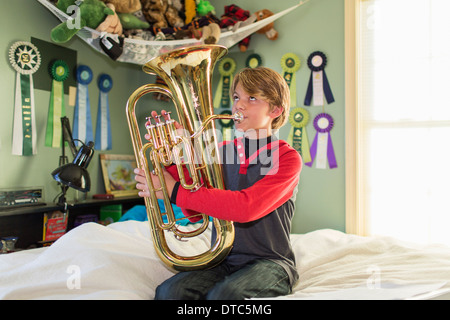 Jungen spielen Tuba im Schlafzimmer Stockfoto