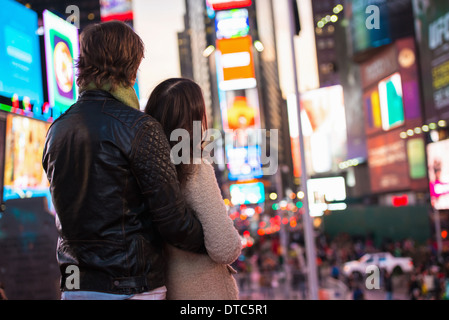 Junges Paar blickte zu Neon Schilder, New York City, USA Stockfoto