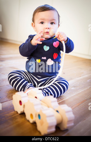 Babymädchen sitzen auf Boden mit Spielzeug Stockfoto