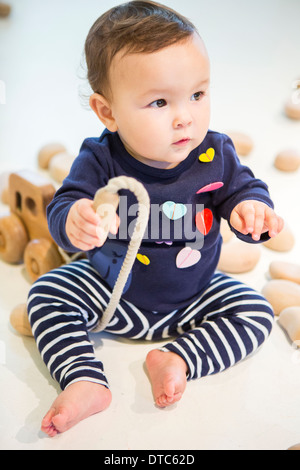 Babymädchen sitzen auf Boden mit Spielzeug Stockfoto