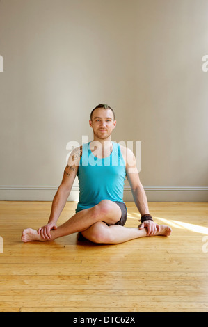 Mann in Cowface-Yoga-pose Stockfoto