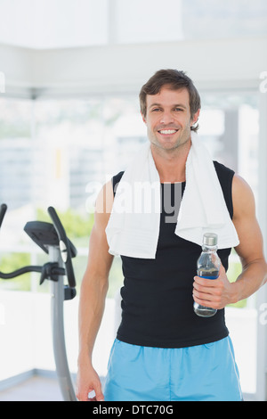 Lächelnder Mann hält Wasserflasche am Spinnen Klasse in hellen Fitnessraum Stockfoto