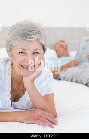 Lächelnde ältere Frau mit Mann im Bett Stockfoto