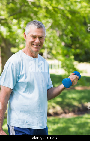 Reifen Mann mit Hantel im Park trainieren lächelnd Stockfoto