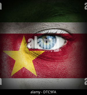 Menschliches Gesicht gemalt mit Flagge von Suriname Stockfoto
