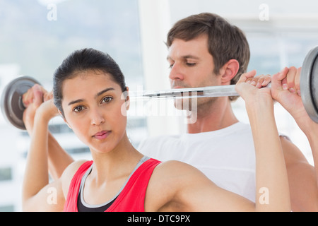 Männlichen Trainer helfen fit Frau, heben Sie die Hantel Stockfoto