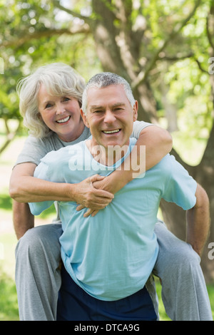 Glücklich reifer Mann trägt Frau im park Stockfoto
