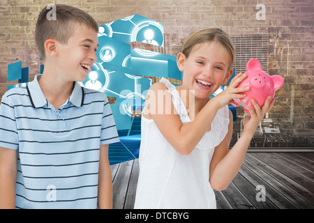 Zusammengesetztes Bild von lächelnden jungen Mädchen verwahrenden Piggy bank Stockfoto