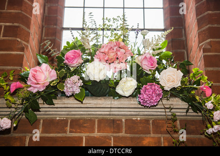 Flower Arrangement / Blütenpracht mit weißen Pfingstrosen und Laub mit Fenster und Ziegel Wand in Christ Church, Woking Stockfoto