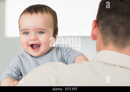 Fröhliche Baby getragen von Vater Stockfoto