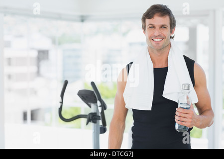 Lächelnder Mann hält Wasserflasche am Spinnen Klasse in hellen Fitnessraum Stockfoto