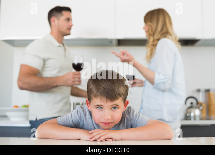 Traurige junge stützte sich auf den Tisch, während Eltern streiten Stockfoto