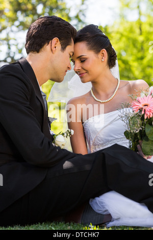 Romantisches Brautpaar sitzen im park Stockfoto