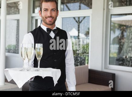 Gut aussehend lächelnden Kellner mit Tablett mit Champagner Stockfoto