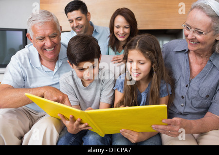 Großfamilie mit Blick auf Album Foto im Wohnzimmer Stockfoto