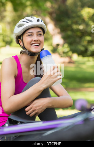 Fit Woman in Helm halten Wasser Flasche im park Stockfoto