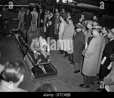 US-Armee Fliegerarzt Oberstleutnant John Paul Stapp (rechts) zeigt den Gee-Whiz Rakete Schlitten für eine Gruppe von Honoratioren mit Howard Hasbrook als Demonstrator 17. April 1956 auf der Edwards Air Force Base, CA in der Maschine zu sitzen. Stockfoto