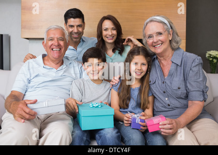Großfamilie auf Sofa mit Geschenk-Boxen im Wohnzimmer Stockfoto
