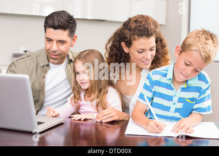 Fröhliche Eltern Färbung und mit Laptop mit ihren Kindern Stockfoto