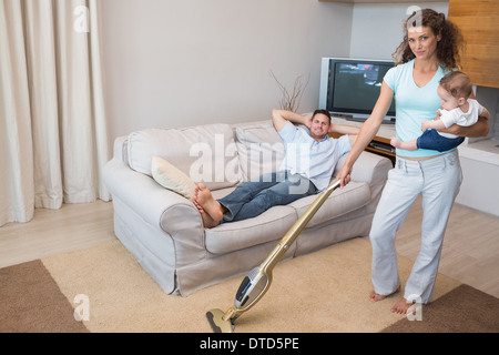 Frau, die Reinigung des Hauses während des Tragens baby Stockfoto