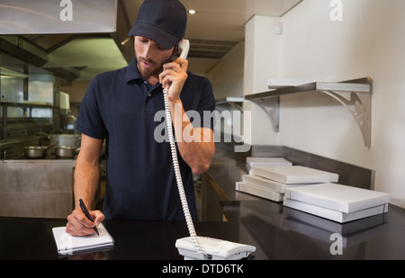 Gut aussehend Pizzamann Auftragsannahme per Telefon Stockfoto