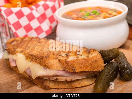 Frisch gebackene Schinken, Schweinefleisch und Schweizer Käse Panini mit Gemüse Suppe und Süßkartoffel Pommes frites serviert. Stockfoto