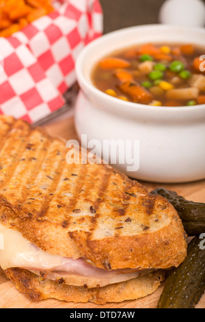 Frisch gebackene Schinken, Schweinefleisch und Schweizer Käse Panini mit Gemüse Suppe und Süßkartoffel Pommes frites serviert. Stockfoto