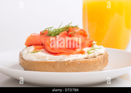 Lecker frisch zubereitete Bagel mit Creme Käse, geräucherter Lachs, Dill und serviert mit frisch gepresstem Orangensaft Stockfoto