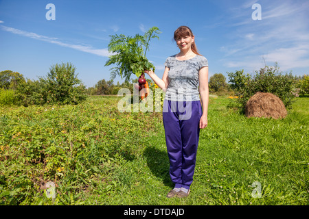 Junge Frau, die eine Garbe von Gemüse in der Hand halten Stockfoto