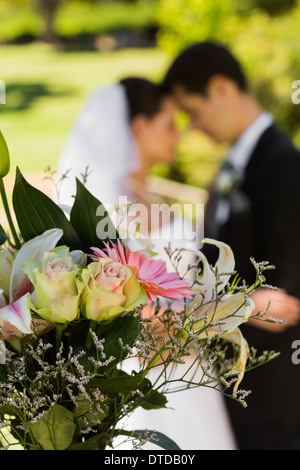 Bouquet mit unscharfen Brautpaar im Hintergrund im park Stockfoto