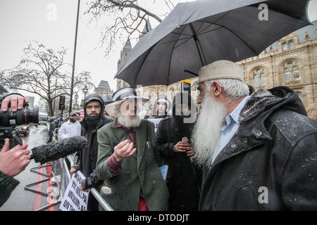 Ein Mitglied der Öffentlichkeit (links) versucht, mit einer Gruppe von radikalen islamistischen Demonstranten in London zu diskutieren. Stockfoto