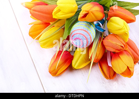 Osterei und Tulpen auf hellem Hintergrund Stockfoto