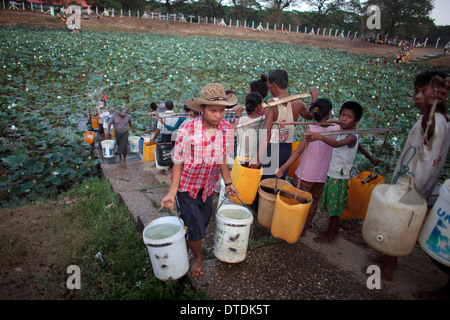 Ein Mann füllen Sie Behälter mit Wasser in einem kleinen See in Dala Township, Myanmar, Montag, 6. Mai 2013 Stockfoto