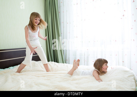 Zwei Schwestern spielen auf Bett zusammen Stockfoto