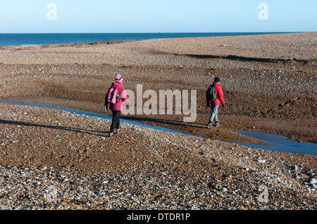 Wanderer auf dem North Norfolk Küstenweg Kreuz eine Bresche in die Schindel spucken Salthouse durch Überschwemmungen verursacht. Stockfoto