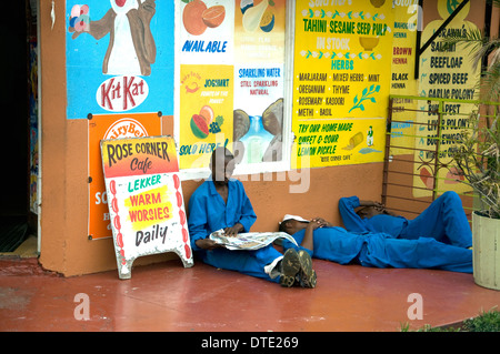 Außen ein kleines Café im Bo-Kaap, Kapstadt, blau-overalled afrikanische Arbeiter entspannen oder Nickerchen während ihrer Mittagspause Stockfoto