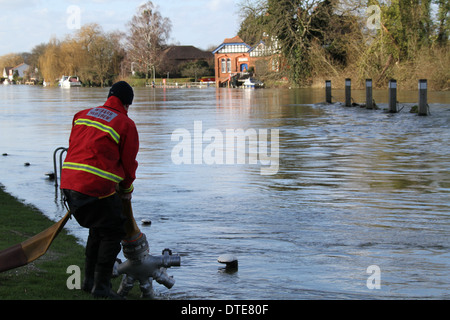 Feuerwehrmann inspiziert einen Schlauch zur Pumpe, Hochwasser von Runnymede in der Themse bei Bell Wier Lock gelegt. Stockfoto