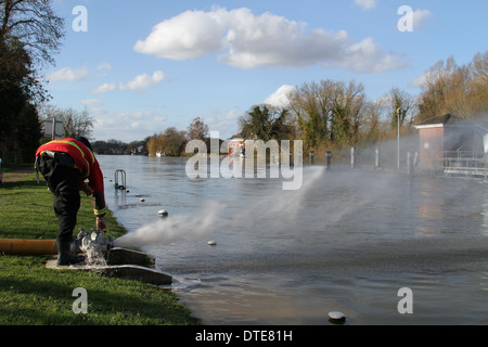 Feuerwehrmann inspiziert einen Schlauch zur Pumpe, Hochwasser von Runnymede in der Themse bei Bell Wier Lock gelegt. Stockfoto