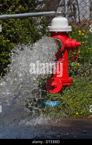 Ein beschädigter roter Hydrant sprüht Wasser auf der Stadtstraße kommunale Dienste echte Frontansicht von oben vertikal oben oben in den USA Hi-res Stockfoto