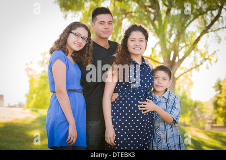 Attraktive hispanische Familienglück mit ihre schwangere Mutter unter freiem Himmel im Park. Stockfoto