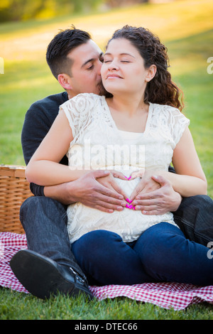 Schwanger hispanische paar machen Herzform mit Hände auf Bauch in der Park-Natur. Stockfoto