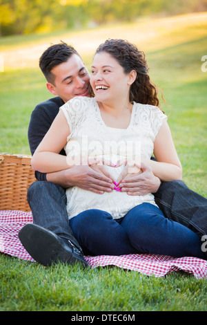 Schwanger hispanische paar machen Herzform mit Hände auf Bauch in der Park-Natur. Stockfoto