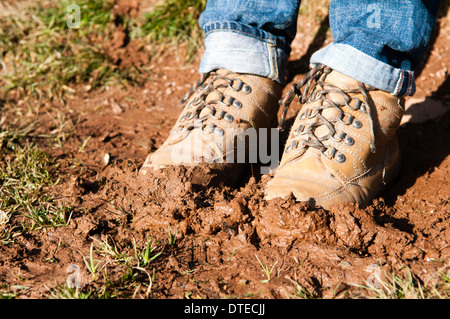 Ein paar schlammige Wanderschuhe in frischem Schlamm in einem Feld stecken in der Landschaft in der Nähe von Dartmouth in Devon Stockfoto