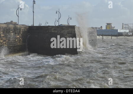 Portsmouth. UK, 15. Februar 2014 1130 bin, die Südküste Englands weiterhin die Auswirkungen der Winterstürme zu spüren. Brechenden Wellen bei Flut mit Southsea Kirmes im Hintergrund © Paul Gordon/Alamy Live News Stockfoto
