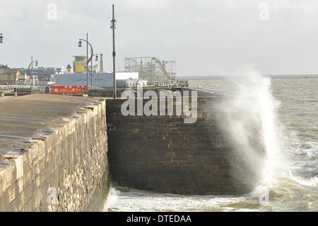 Portsmouth. UK, 15. Februar 2014 1130 bin, die Südküste Englands weiterhin die Auswirkungen der Winterstürme zu spüren. Brechenden Wellen bei Flut mit Southsea Kirmes im Hintergrund Credit: Paul Gordon/Alamy Live News Stockfoto