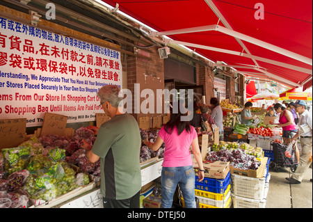 Käufer, die Wahl der Lebensmittel auf Ständen außerhalb ein Lebensmittelgeschäft in Chinatown, Toronto Stockfoto