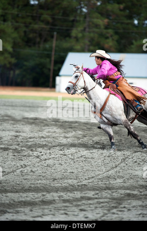 Ein Cowgirl auf einem Pferd Reiten in vollem Galopp mit Pistole gezogen. Annie Oakley Boom Tage Festival in Pinehurst, North Carolina. Stockfoto