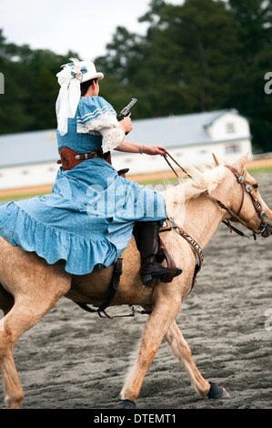 Ein Cowgirl auf einem Pferd Reiten in vollem Galopp mit Pistole gezogen. Annie Oakley Boom Tage Festival in Pinehurst, North Carolina. Stockfoto