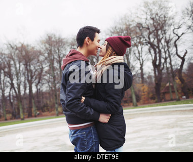 Gemischte Rassen Teenager-paar zu einen leidenschaftlichen Kuss im Park haben. Hübscher junger Mann und schöne junge Frau in warme Kleidung. Stockfoto